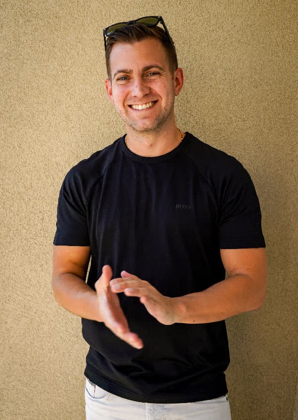 Rob Brautigam, smiling, in a black T-shirt against a sand-colored wall